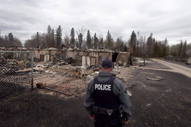 A police officer looks over a fire-damaged building in the Abasand neighbourhood in Fort McMurray, Alta., on May 9, 2016.